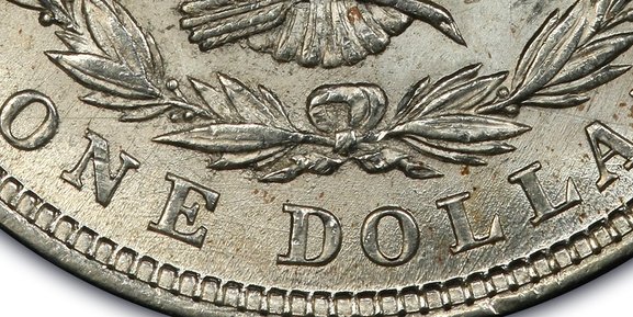 A picture of the reverse of a 1921 Morgan Dollar showing pitted, crater-like textures around the eagle and lettering due to die corrosion.